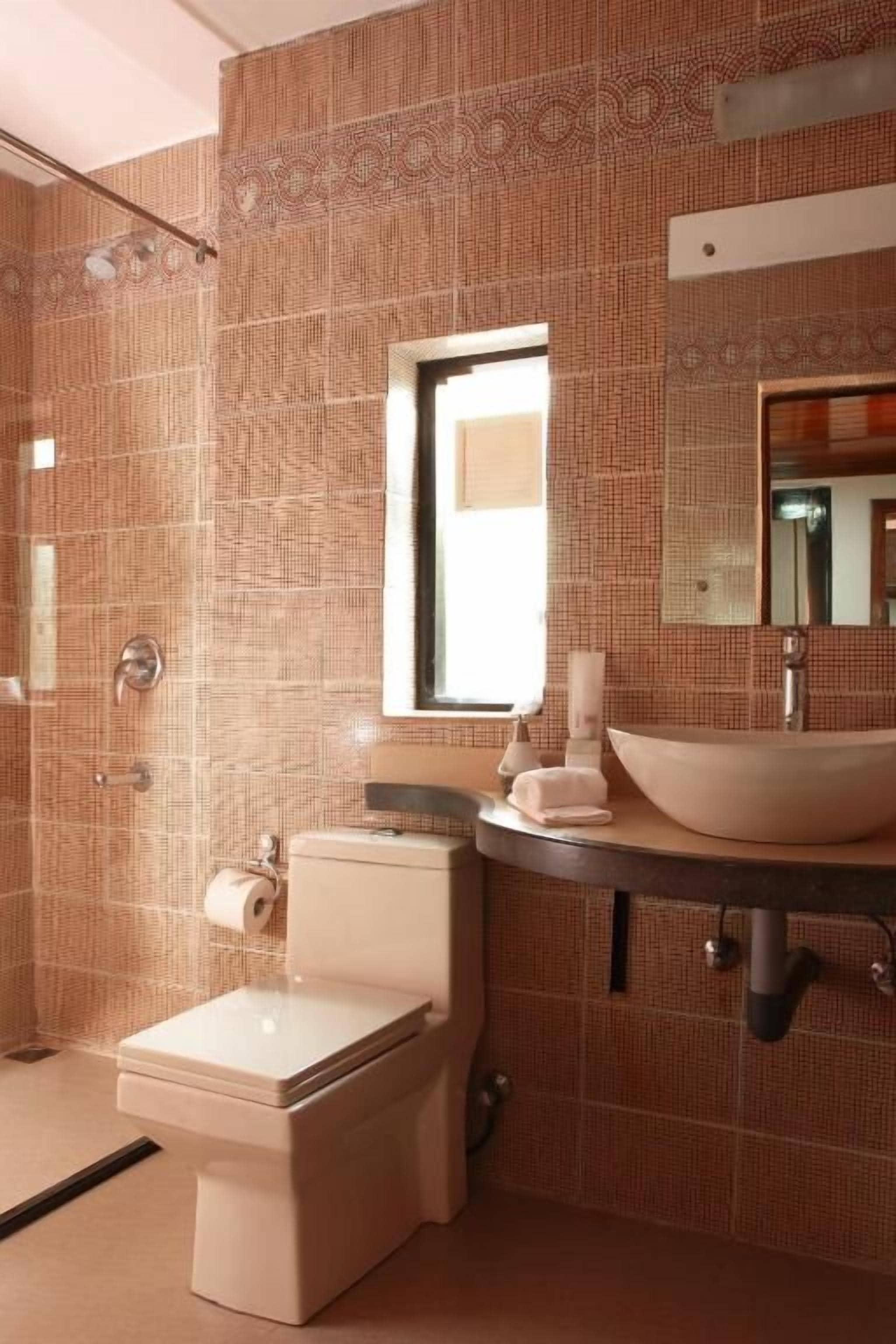 A bathroom with a toilet, sink, and mirror.