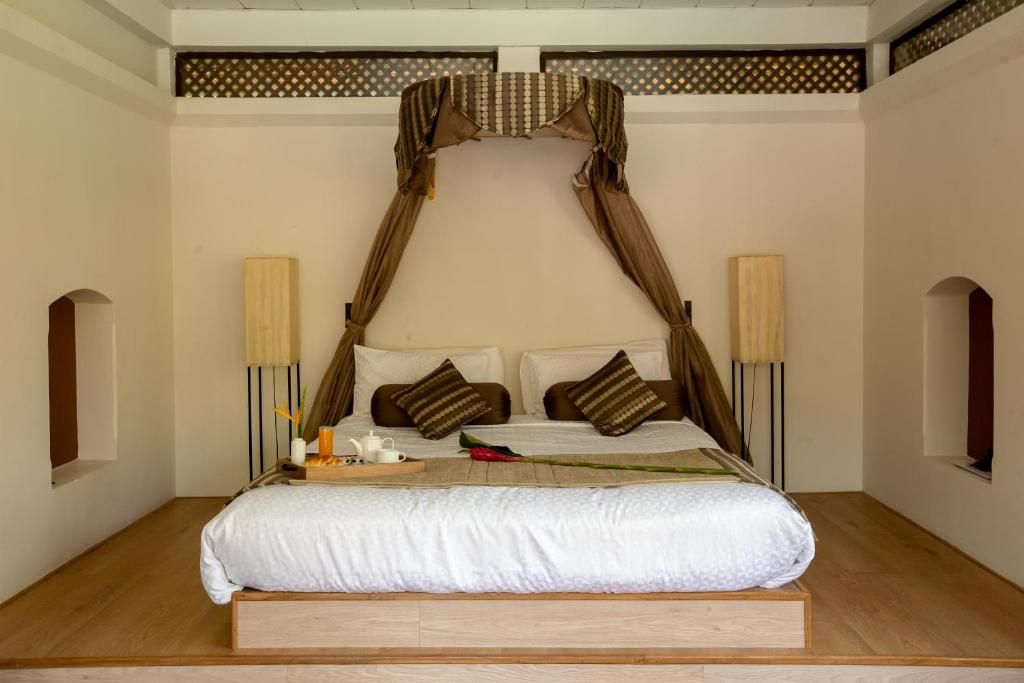 Un dormitorio con cama a dosel, dos lámparas de noche y piso de madera.