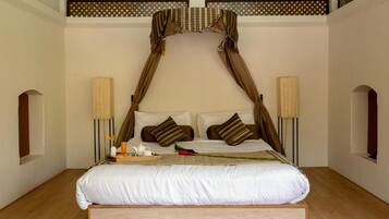Un dormitorio con cama a dosel, dos lámparas de noche y piso de madera.