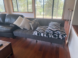 Una sala moderna con un sofá de cuero oscuro, cojines estampados y una mesa de centro de madera.