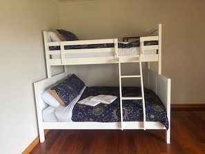 A bunk bed with a ladder, white headboard, and a dark blue bedspread with star patterns.
