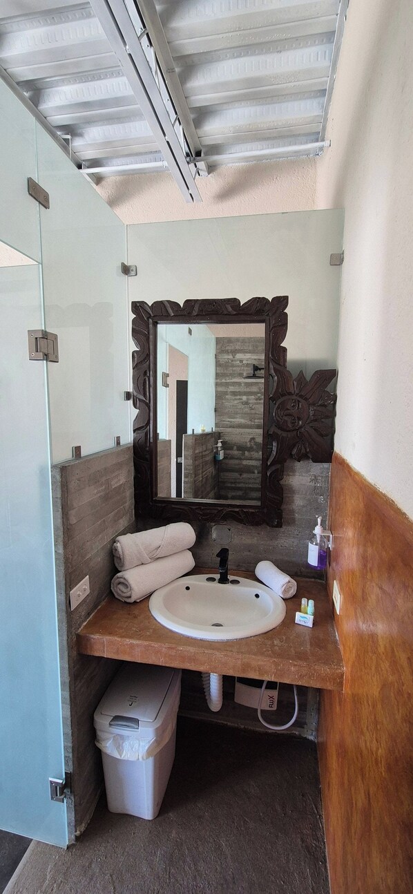 A bathroom with a large mirror, a sink, and a towel rack.