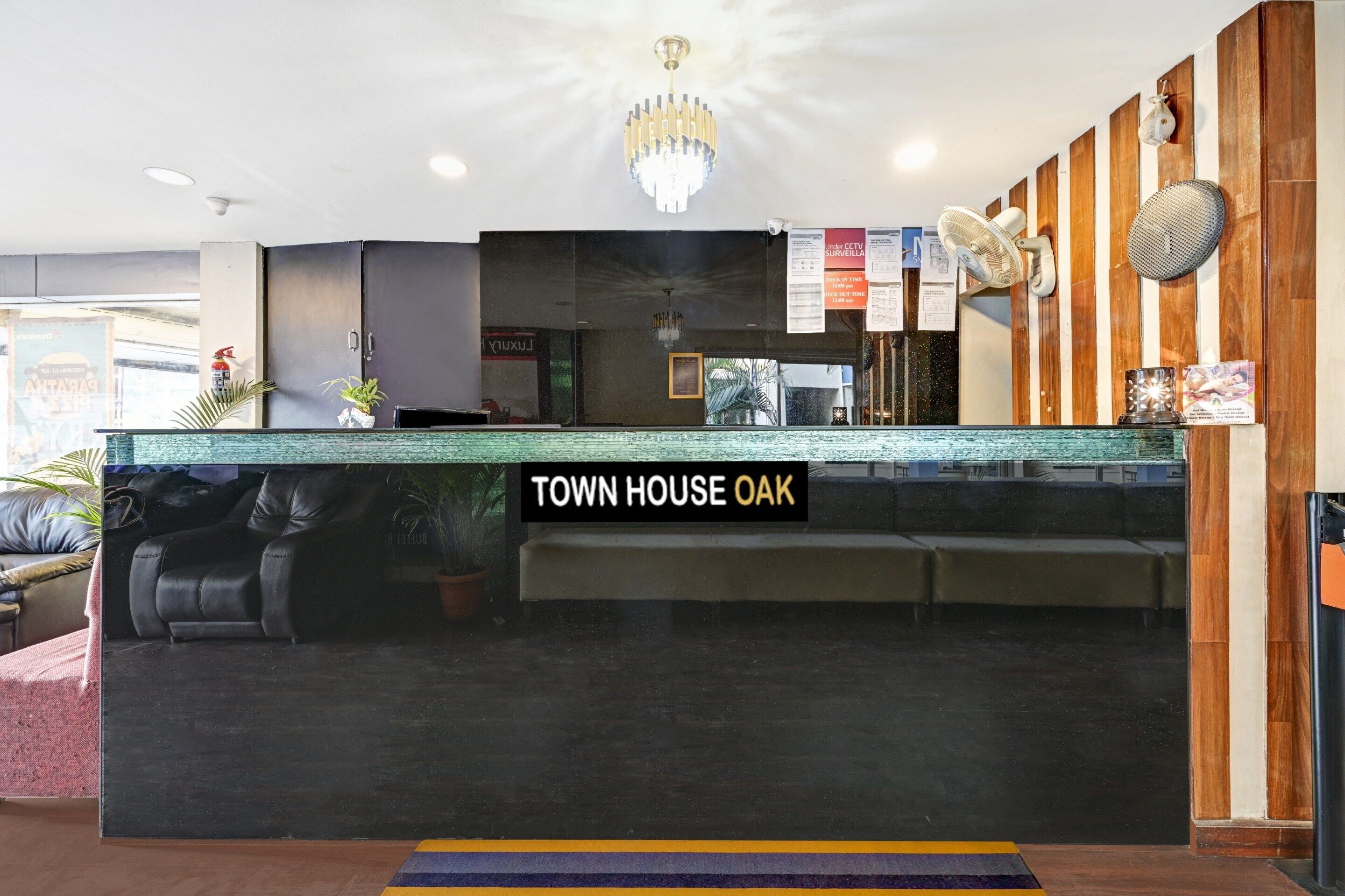 A reception desk with a 'TOWN HOUSE OAK' sign, a chandelier, a fan, and a wooden wall panel.