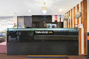 En receptionsdisk med et skilt, der siger 'TOWN HOUSE OAK', en lysekrone, en ventilator og en trævæg.