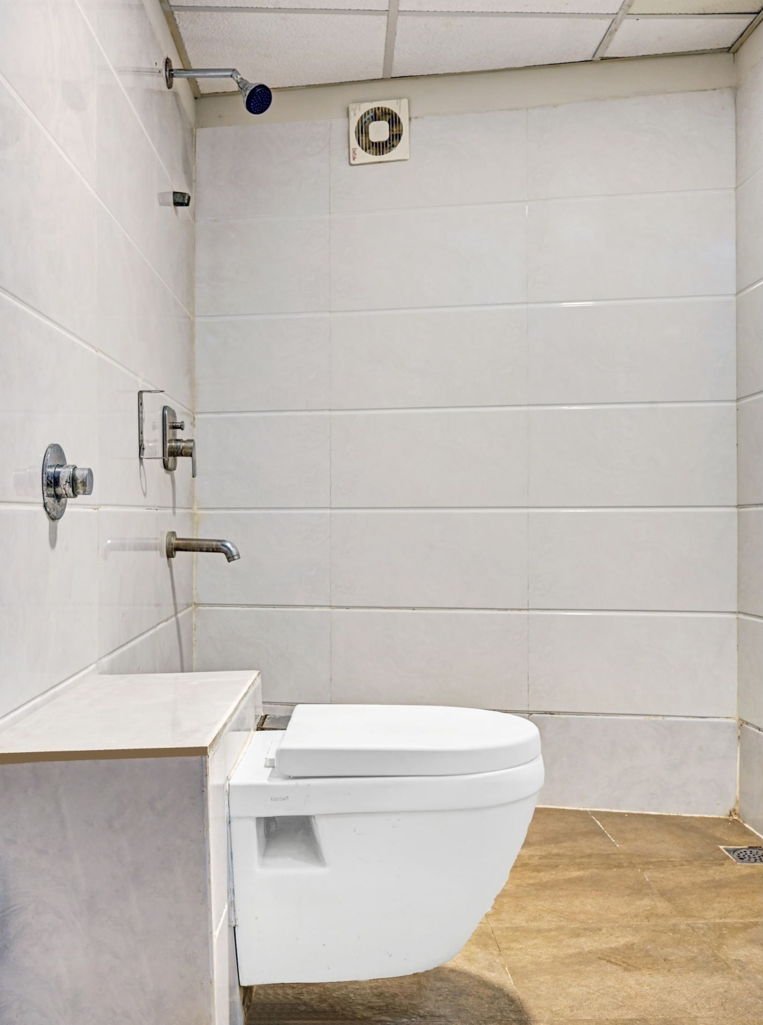 Une salle de bain avec des toilettes blanches, un espace douche et un sol carrelé.