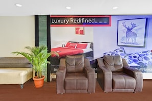 Et lobbyområde med en sofa, to læderstole, en potteplante og et stort plakat med teksten 'Luxury Redefined'.