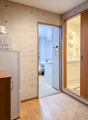 A compact kitchen with a refrigerator, a microwave, and a wooden cabinet. - HANASTAY UJUN TSUTENKAKU (Osaka)