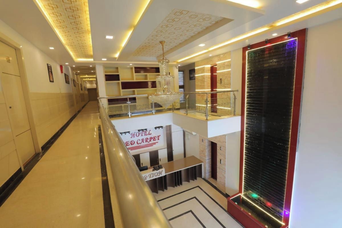 A hotel lobby with a reception desk, a chandelier, a water feature, and a patterned floor.