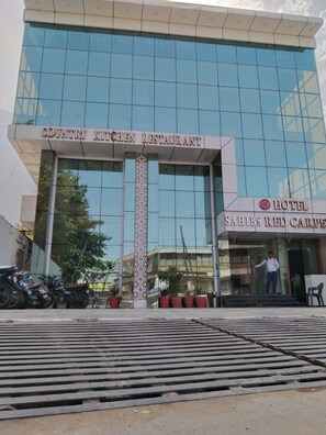 Un edificio con un letrero que indica 'Country Kitchen Restaurant' y 'Hotel Sahibs Red Carpet'.