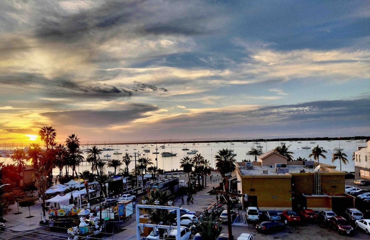 Un puerto deportivo con barcos, un estacionamiento y un edificio de techo plano.