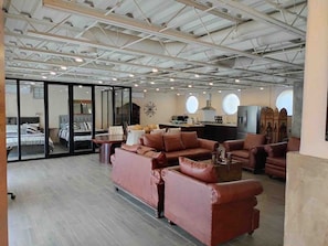 En rummelig opholdsstue med lædersofaer, et sofabord og et køkken i baggrunden.