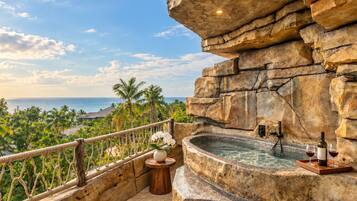 A stone balustrade overlooking a pool with a view of the ocean and palm trees.