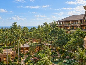Un resort con piscina rodeada de vegetación tropical y vistas al océano.