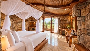 Un dormitorio con pared de piedra, cama con ropa de cama blanca, dosel y vistas al exterior.