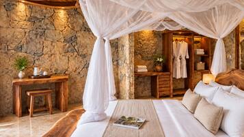 A bedroom with a stone wall, a wooden bed, a bedside table, and a hanging canopy.