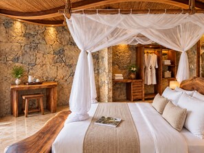 Un dormitorio con pared de piedra, cama de madera, mesita de noche y dosel colgante.