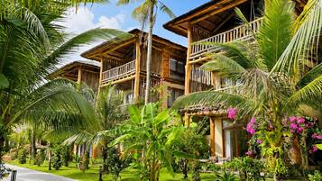 Ein Resort mit mehreren Holzhäusern, einem gepflasterten Weg und üppiger tropischer Vegetation.