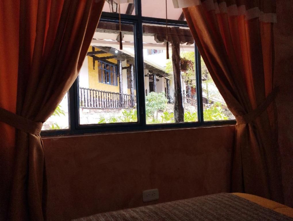 A room with a window, curtains, and a bed.