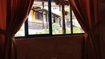 A room with a window, curtains, and a bed.