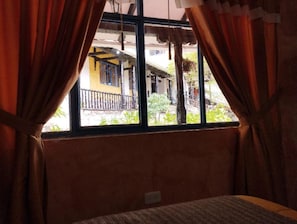 A room with a window, curtains, and a bed.