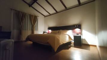 Habitación de hotel con cama, mesita de noche y ventana con cortinas.
