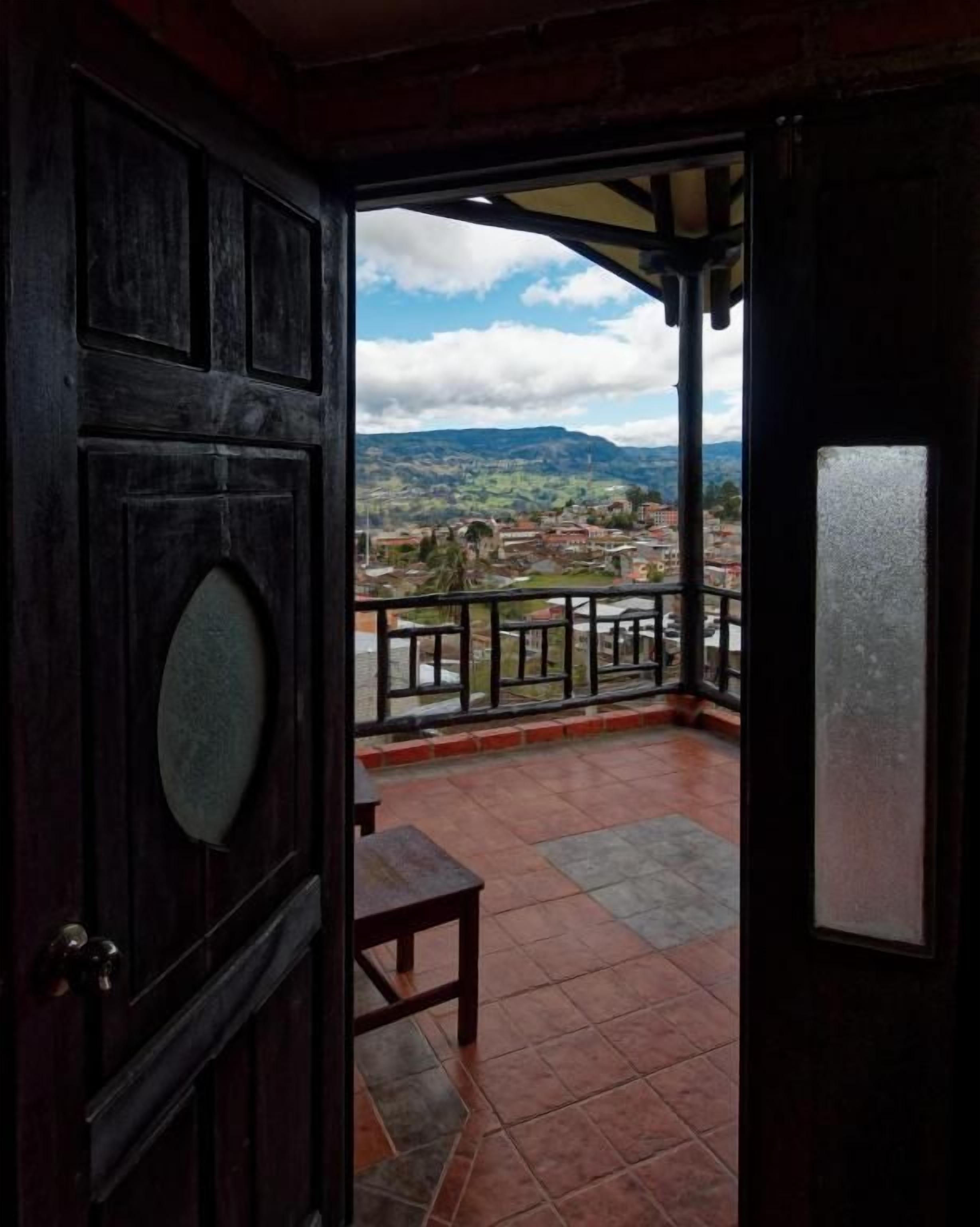 Una puerta de madera que da a un balcón con vistas a un pueblo y montañas.