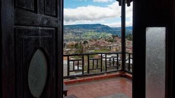 Una puerta de madera que da a un balcón con vistas a un pueblo y montañas.