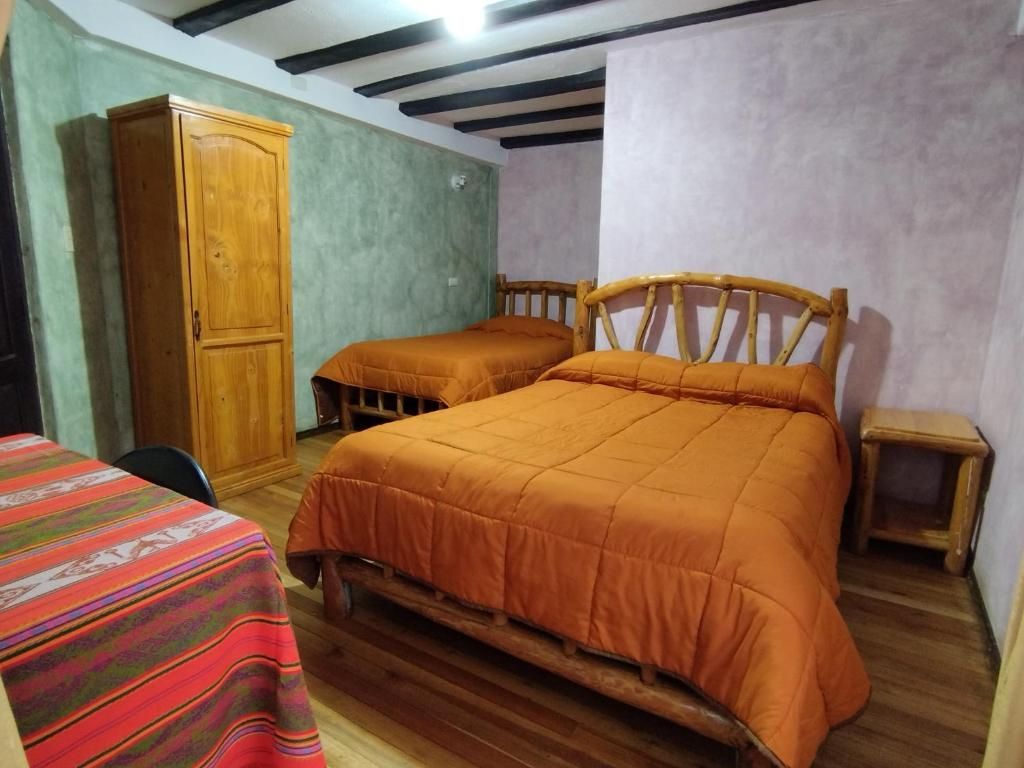 Una habitación con dos camas de madera, un armario y una mesita.