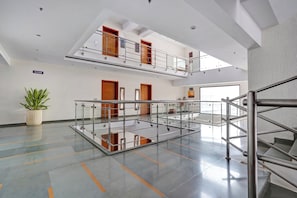 Ein geräumiges, mehrgeschossiges Atrium mit Glasboden, Metallgeländern und einer Treppe.