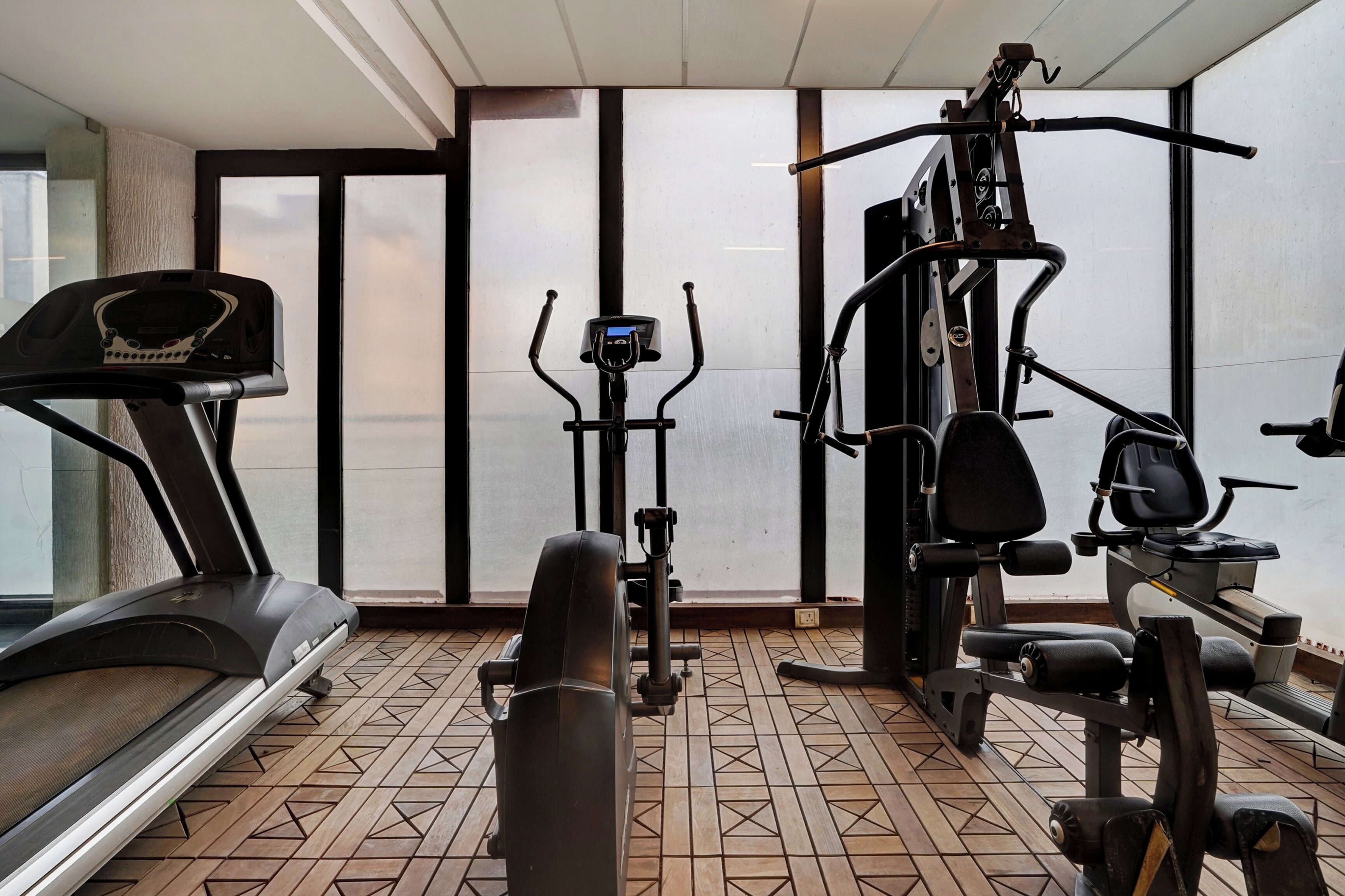 Un gimnasio con cinta de correr, elíptica y máquinas de pesas.