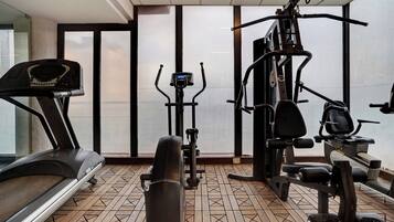 Un gimnasio con cinta de correr, elíptica y máquinas de pesas.