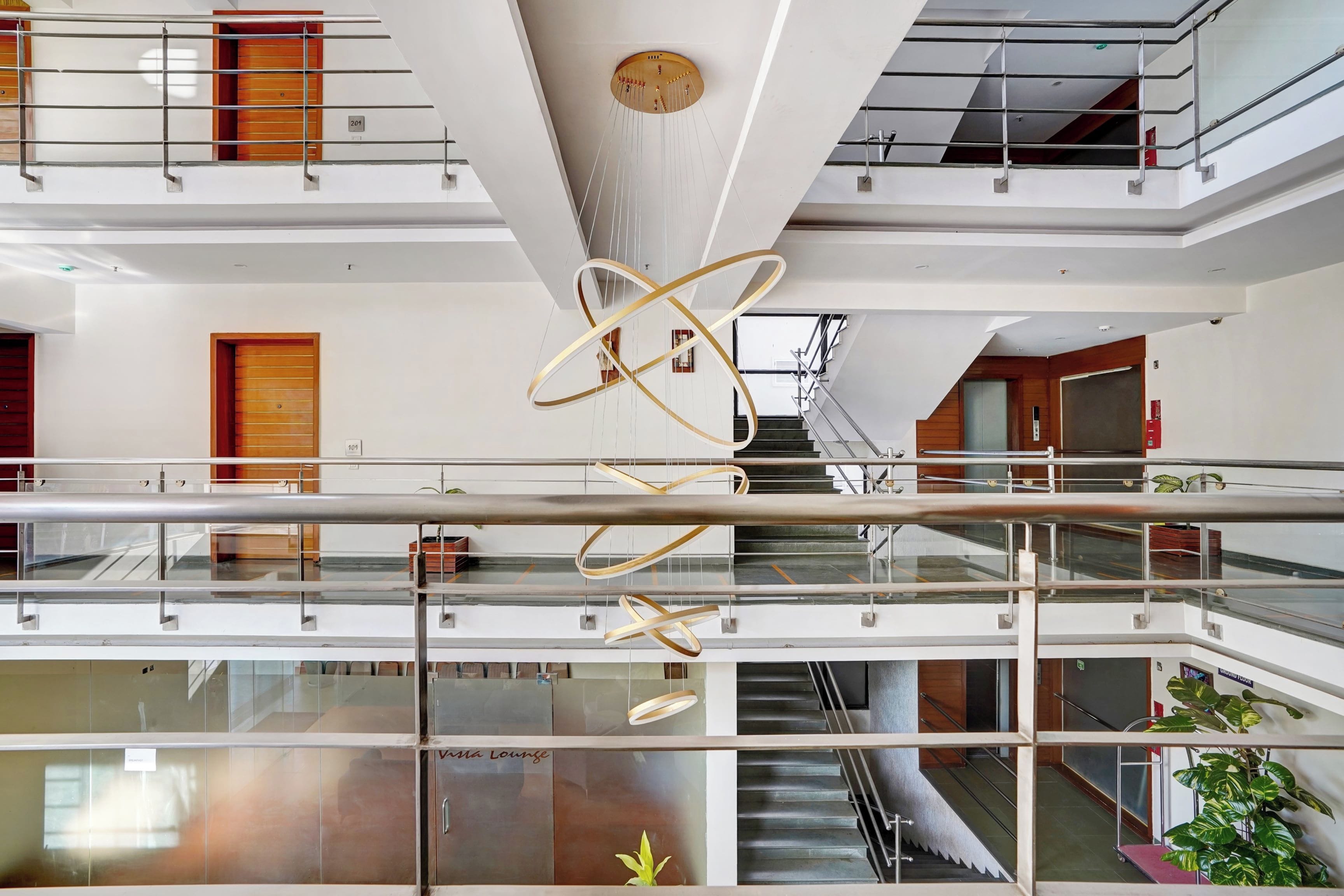 Un interior de varios niveles con una escalera espiral central, barandillas de vidrio y una estructura colgante decorativa.