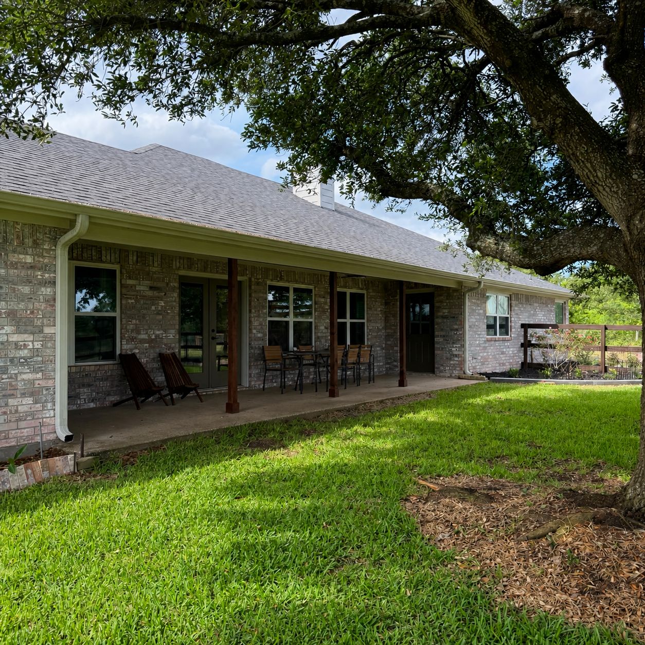 A two-story house with a covered porch, brick exterior, and a lawn.