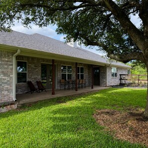 A two-story house with a covered porch, brick exterior, and a lawn. - Private 11-Acre Retreat Near Texas A&M (College Station)
