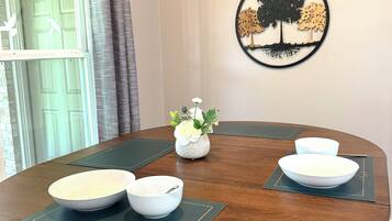 A round dining table with four white bowls and a vase with white flowers.