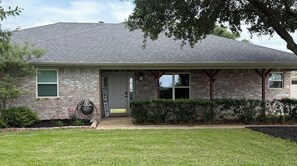 A residential house with a brick facade, a front door, a welcome sign, and a well-maintained lawn. - Private 11-Acre Retreat Near Texas A&M (College Station)