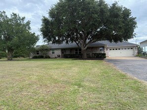 A residential house with a garage, a lawn, and a large tree.