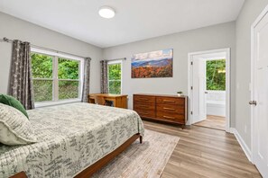 Une chambre à coucher avec un lit, un bureau, une commode et un tableau.