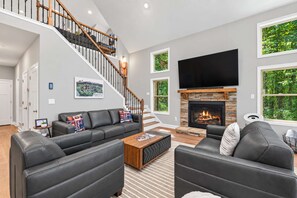 Un salon moderne avec une cheminée, un escalier et un grand téléviseur.