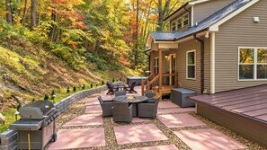Une terrasse avec des meubles d’extérieur, un barbecue et une maison dotée d’une véranda.