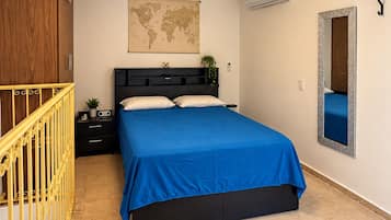 Une chambre à coucher avec un lit, une carte accrochée au mur, un miroir et un escalier.