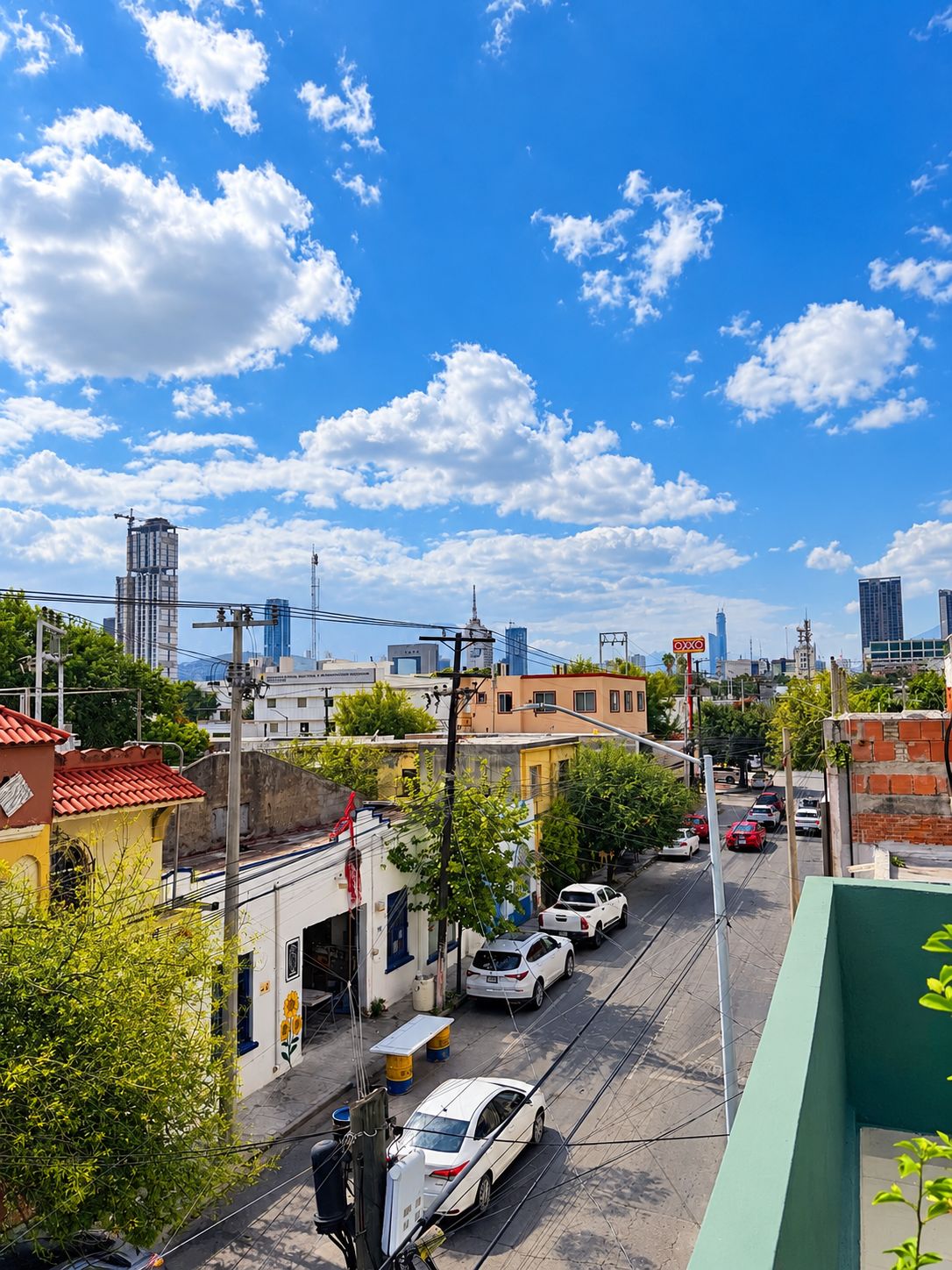 A city street with buildings, cars, and a clear blue sky.