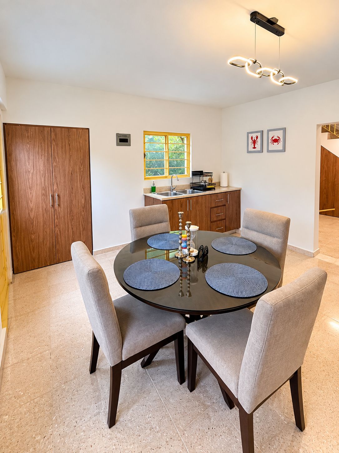 Un coin repas comprenant une table ronde, six chaises et un luminaire suspendu au design moderne.