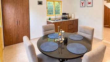Un coin repas comprenant une table ronde, six chaises et un luminaire suspendu au design moderne.