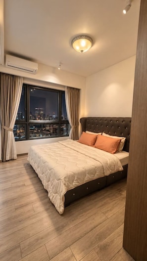 A bedroom with a city view, a bed with a dark headboard, and an air conditioning unit. - Wake up to stunning KL skyline views in this bright 2-bedroom in Bukit Bintang.. (Kuala Lumpur)