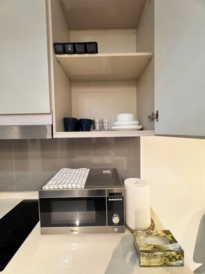 A kitchen with a microwave, a roll of paper towels, and a box of salt. - Wake up to stunning KL skyline views in this bright 2-bedroom in Bukit Bintang.. (Kuala Lumpur)
