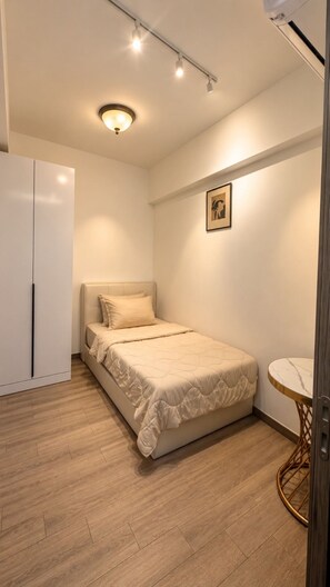 A bedroom with a bed, a wardrobe, a round table, and a picture on the wall. - Wake up to stunning KL skyline views in this bright 2-bedroom in Bukit Bintang.. (Kuala Lumpur)