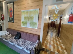 Et hotellobby med en trævæg, en sofa, et indrammet billede og en gang med mønstret gulv.