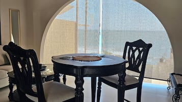 Un coin repas avec une table ronde, deux chaises et une vue à travers une fenêtre semi-circulaire.