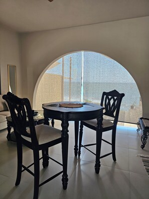 Un coin repas avec une table ronde, deux chaises et une vue à travers une fenêtre semi-circulaire.